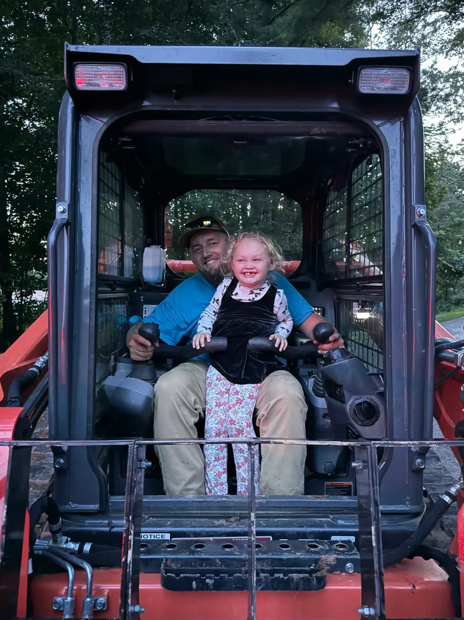 Owner Brandon Medley and his daughter in the cab of a skid steer